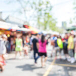 Blurred image pf people shopping at market fair in sunny day