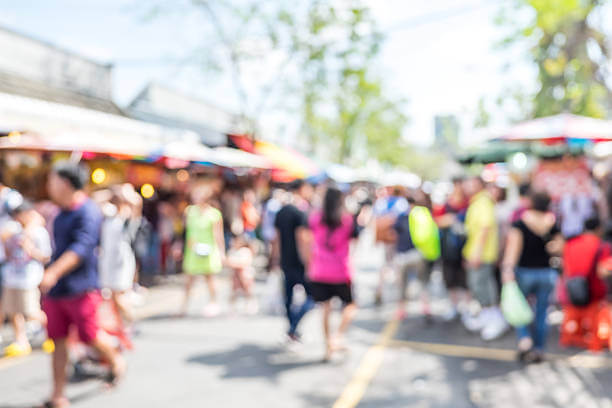 Blurred image of people shopping at market fair on a sunny day - centralize community events